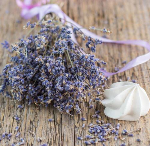 A bouquet of dried lavender with a white meringue on a rustic wooden surface.