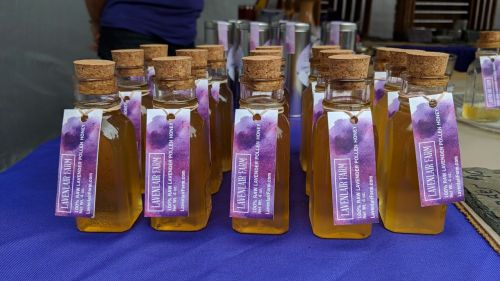 Bottles of lavender oil with cork stoppers and colorful labels, arranged on a table.