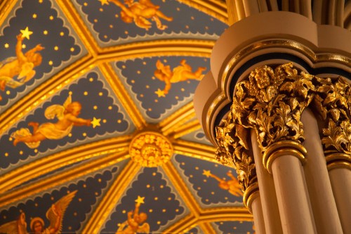Ornate ceiling with golden angels and stars, featuring a detailed column with intricate floral designs.