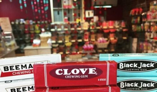 A display of various chewing gum brands, including Clove, Beeman's, and Black Jack, stacked on a table.