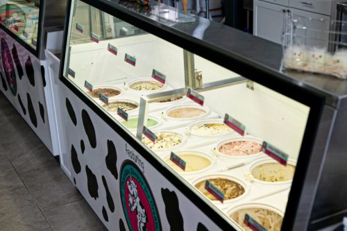 A display case filled with various flavors of ice cream in a colorful shop.