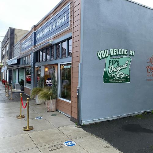 Exterior of Pip's Original Doughnuts & Chai, featuring a welcoming sign and a queue barrier outside.