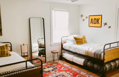 A cozy bedroom with two beds, a mirror, a small table, and decorative wall art in a bright, inviting space.