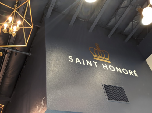 Interior view featuring a dark wall with the text "SAINT HONORÉ" and a crown logo, along with decorative lighting.