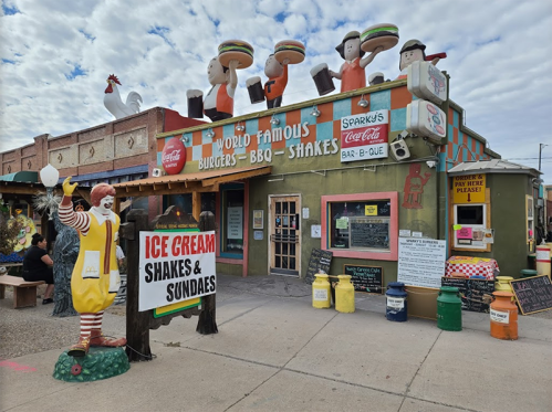 Colorful restaurant exterior featuring burgers, BBQ, and shakes, with a Ronald McDonald statue and a sign for ice cream.