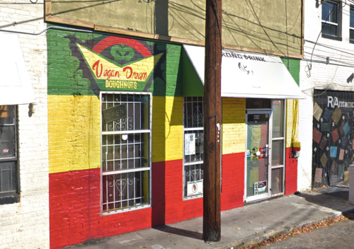 Colorful storefront with a mural featuring red, yellow, and green stripes, labeled "Vegan Dream Doughnuts."