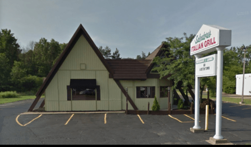 A triangular-roofed building with a sign for "Saddleback Italian Grill" and a parking lot in front.