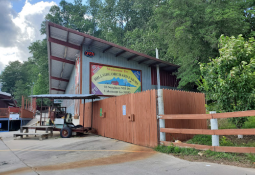 A red barn-like building with a sign reading "Welcome to Hillside Orchard Farm" surrounded by trees in Lakeview, GA.