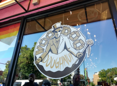 Logo of Voodoo Doughnut featuring a character in a top hat holding a doughnut, displayed on a shop window.