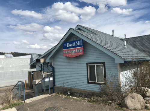 A blue building with a sloped roof, featuring signs for "The Donut Mill" and "The Ice Cream Parlor."