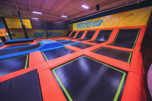 A vibrant indoor trampoline park featuring interconnected trampolines with orange and black surfaces.