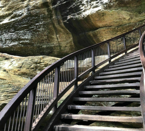 A winding metal staircase leads through a rocky landscape, surrounded by textured stone walls.