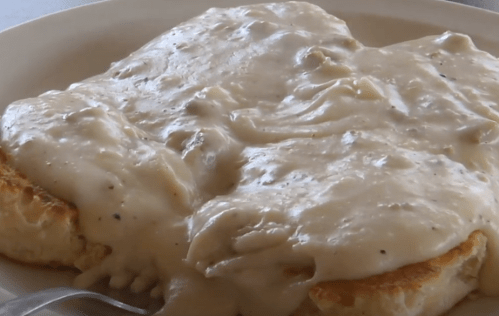 A plate of biscuits smothered in creamy sausage gravy, served warm and ready to eat.