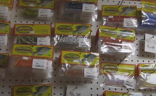 A display of various fishing lures in colorful packaging on a pegboard.