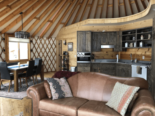 Cozy interior of a yurt featuring a living area, dining space, and modern kitchen with wooden accents.