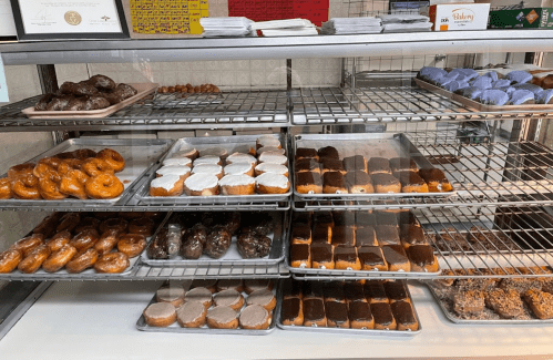 A display case filled with various donuts, including glazed, chocolate-covered, and frosted varieties.