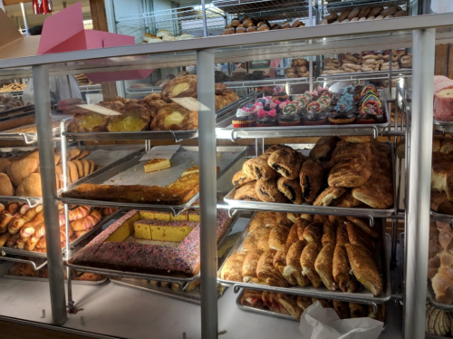 A display case filled with various baked goods, including pastries, donuts, and cakes.