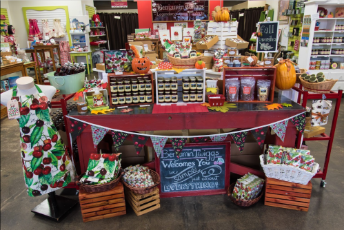 A colorful display of seasonal products, including jars, snacks, and decorations, in a charming store setting.