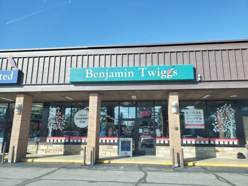 Storefront of Benjamin Twigg's featuring a sign, windows with pie and gift displays, and a clear blue sky.