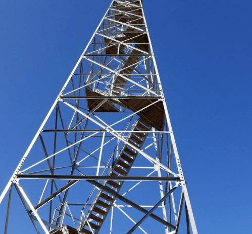 A tall metal tower with a spiral staircase against a clear blue sky.