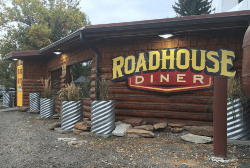 Exterior of the Roadhouse Diner, featuring a log cabin design and decorative planters.