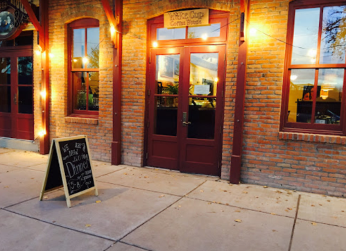 A cozy coffee house with a brick exterior and a chalkboard sign outside, inviting customers for dinner.