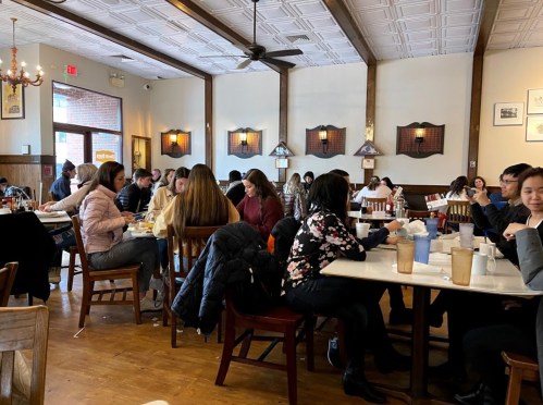 A busy restaurant interior with diners at tables, enjoying meals in a cozy, well-lit atmosphere.