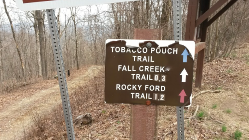 Trail sign indicating Tobacco Pouch Trail, Fall Creek Trail, and Rocky Ford Trail with distance markers.