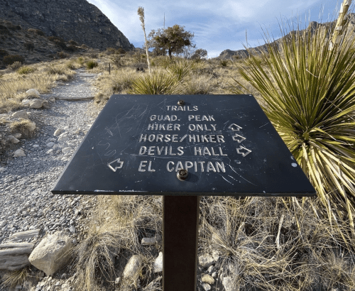 Trail sign indicating directions for hiking, horseback riding, and destinations like El Capitan and Devil's Hall.