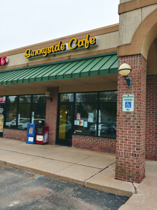 Exterior of Sunnyside Cafe, featuring a green awning and brick facade, with reserved parking sign visible.