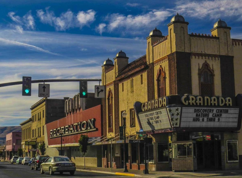 Historic buildings with a marquee, street signs, and a blue sky in a small town setting.