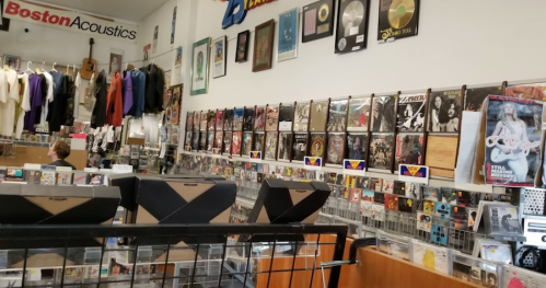 A music store interior featuring walls lined with albums, posters, and display racks of CDs and vinyl records.
