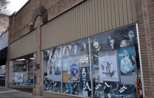 Storefront with large windows displaying various music posters and memorabilia.