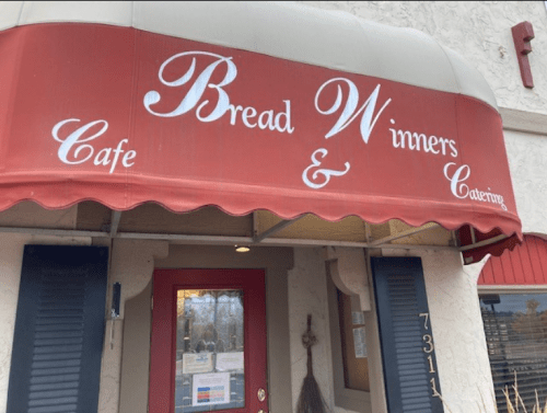Red awning with the text "Bread Winners Cafe & Catering" above the entrance of a building.