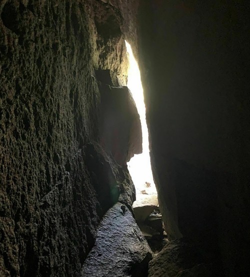 A narrow crevice between large rocks, with bright light visible at the far end.