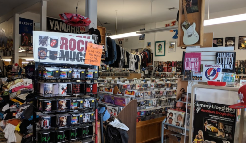 A cluttered store interior filled with music memorabilia, clothing, and various CDs on display.
