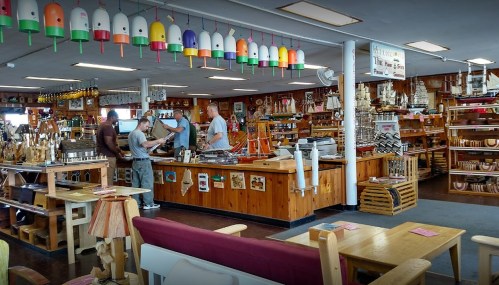A cozy shop interior with wooden decor, colorful hanging lights, and customers browsing various handcrafted items.
