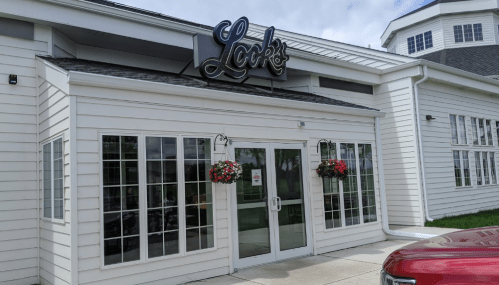 Exterior of a building with a sign reading "Look's," featuring large windows and hanging flower baskets.