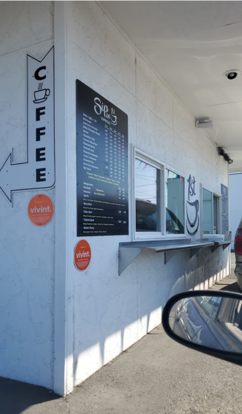 Drive-thru coffee shop with a menu board and signage, featuring a window for ordering and colorful decorations.