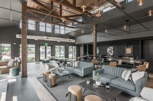 Modern lounge area with stylish furniture, wooden beams, and large windows, creating a bright and inviting atmosphere.