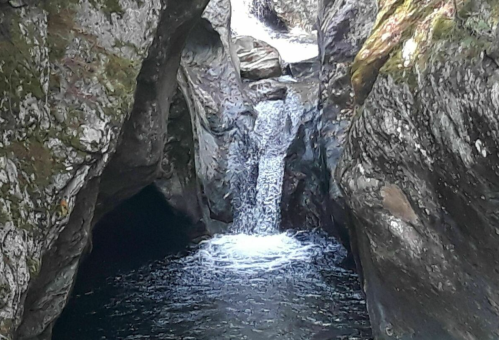 A small waterfall cascades between rocky cliffs, creating a serene pool of water below.
