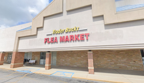 Exterior of Trader Bucks Flea Market, featuring a large sign with red lettering on a beige building.