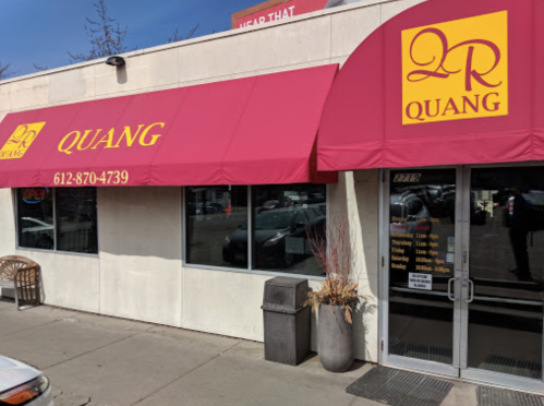 Exterior of Quang restaurant featuring a red awning with the name "QUANG" and contact number, on a sunny day.