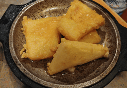 Fried golden squares of dough served on a small, round plate.