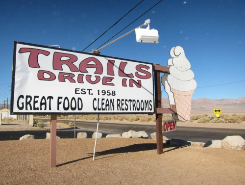 Sign for Trails Drive-In, established 1958, featuring ice cream graphic, promoting great food and clean restrooms. Open.