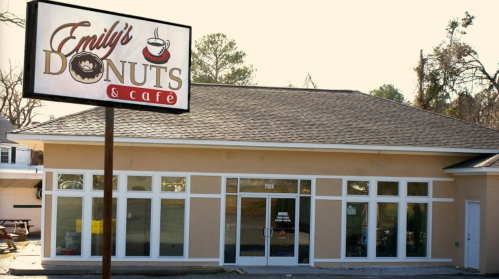 A café building with a sign reading "Emily's Donuts & Café," featuring large windows and a welcoming entrance.