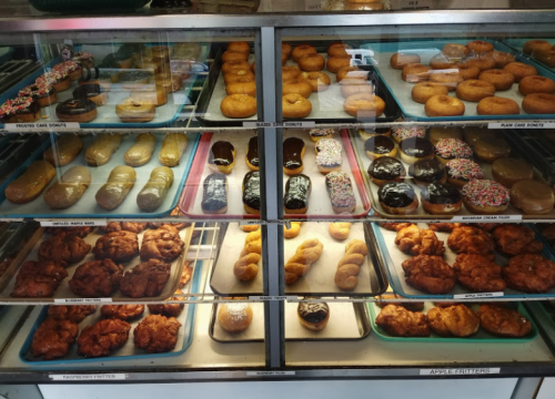A display case filled with various types of donuts, including glazed, chocolate, and apple fritters.