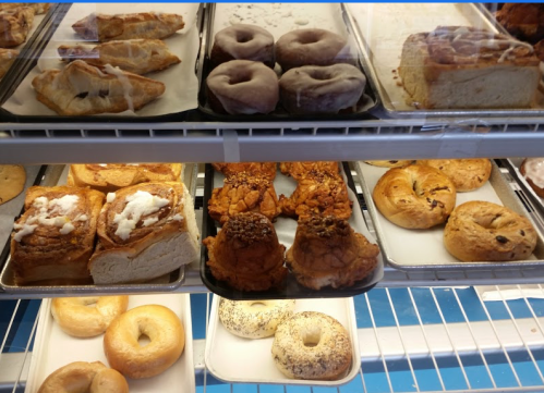 A display case filled with various pastries, including donuts, bagels, and sweet rolls.