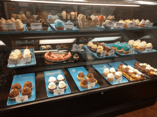A display case filled with various cupcakes, featuring different flavors and colorful frosting.