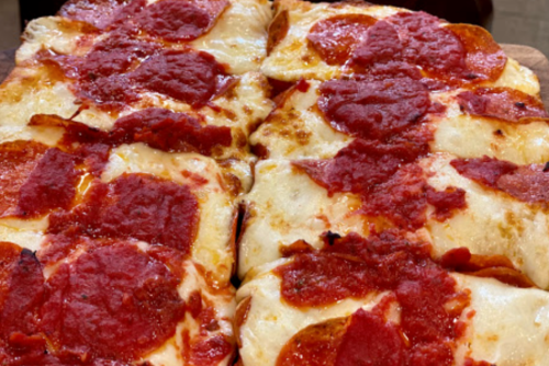 A close-up of a pizza topped with pepperoni and a rich tomato sauce on a golden crust.
